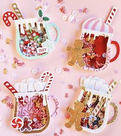 three christmas tea cups with gingerbreads and candy canes in them on a pink background