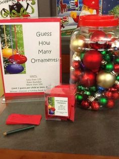 a glass jar filled with christmas ornaments next to a sign that says guess how many ornaments