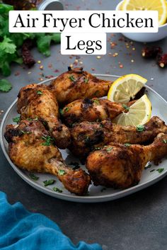 air fryer chicken legs on a plate with lemon wedges