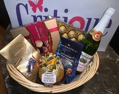 a wicker basket filled with champagne, chocolates and other items next to a sign