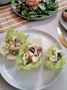 some food is sitting on a white plate and next to a bowl of salads