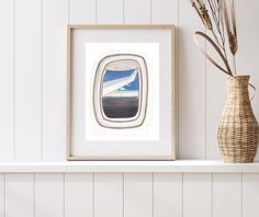 an airplane window is shown on the shelf next to a vase with dry grass in it