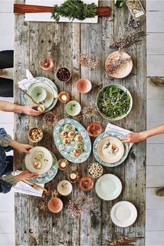 several people sitting around a wooden table with plates and bowls on it