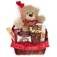 a teddy bear sitting in a basket filled with chocolates, candy and candies