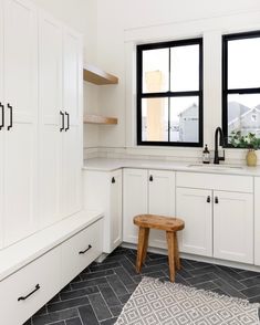 a kitchen with black and white tile flooring next to two large windows on the wall