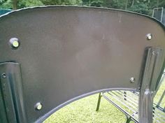 a metal bench sitting on top of a lush green field