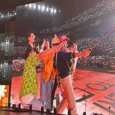 two men and a woman on stage with their arms in the air