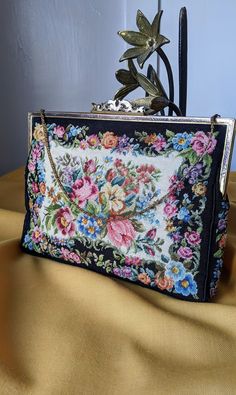 "Vintage petit point purse attributed to Maria Stransky, \"The Queen of Petit Point\", Austria. Almost identical to the model on their website, \"Flora Schwarz\", embroidered on both sides, 900 stitches per square inch. Beautiful etched filigree frame with a gorgeous ornamental clasp, flat wrist chain. Beige cloth interior, one interior pocket. In pristine condition with no visible flaws, minor patina on the metal frame. 8 x 6 x 1\" Missing label." Filigree Frame, Wrist Chain, Beaded Bags, Clutch Handbag, The Queen, Le Point, Evening Bags, Purses And Handbags, Austria