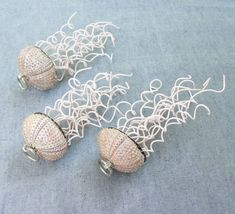 three white beaded balls sitting on top of a blue cloth