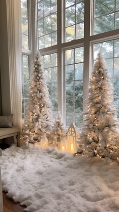 white christmas trees in front of a window with lit candles on the windowsills