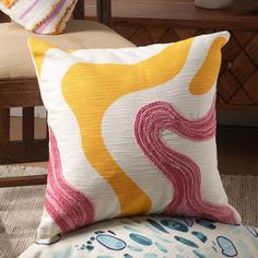 a yellow and pink pillow sitting on top of a chair