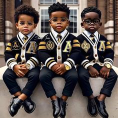 three young boys wearing black and gold uniforms sitting on top of a cement block in front of a building