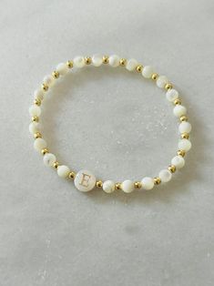 - Beautiful dainty pearl initial bracelet that makes a gorgeous bracelet gift. Soft and delicate with tiny 18 gold filled beads and freshwater shell initial bead. Coordinating pieces in shop. Beaded on high quality stretch cord and secured. - 3mm 18k gold filled beads   4mm mother of pearl beads    8mm freshwater shell initial bead. - Purchase is sent in a white velvet drawstring jewelry bag, making the perfect bracelet gift for bridesmaid, bracelet for mom, anyone special or just yourself. - To care for your bracelet, please roll on and off wrist. Repeated stretching can wear the elastic over time. Avoid excessive contact with water and chemicals. - We highly recommend measuring your wrist before ordering. Please see our sizing guide in the listing photos.  - We strive to get orders out a Elegant Pearl Bracelet With Letter Beads, Elegant Pearl Beaded Bracelets With Letter Beads, Elegant Bracelets With Letter Beads For Gifts, Elegant Beaded Bracelets With Letter Beads As Gift, Elegant Letter Beads Bracelet For Gift, Elegant Beaded Bracelets With Letter Beads For Gift, Elegant Bracelet With Round Letter Beads, Elegant Pearl Bracelet With Letter Beads As Gift, Elegant Charm Bracelet With Letter Beads