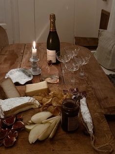 a wooden table topped with cheese and crackers next to a bottle of wine on top of it