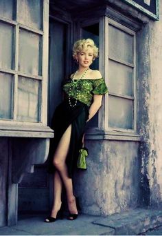 a woman in a green dress leaning against a window