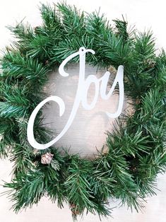 a christmas wreath with the word joy painted on it