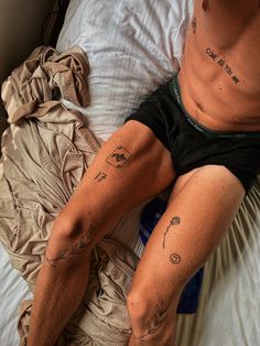 a man with tattoos on his legs laying in bed