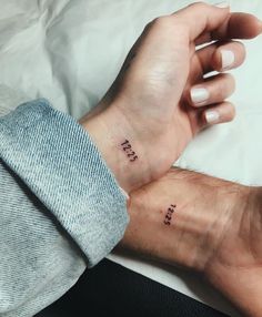 two hands holding each other with the word love tattooed on their left wrist and right hand