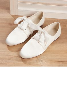 a pair of white shoes sitting on top of a wooden floor