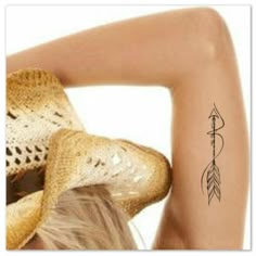 the back of a woman's head with a hat on her head and an arrow tattoo