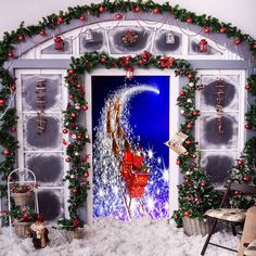 an open door decorated with christmas decorations and lights in front of a snow covered room