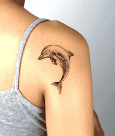 a woman's arm with a dolphin tattoo on the left side of her shoulder