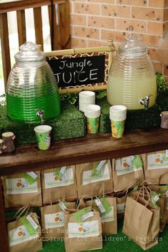 a table topped with bags and cups filled with liquid next to a sign that says jungle juice