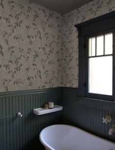 an old fashioned bathtub sits in the corner of a bathroom with floral wallpaper