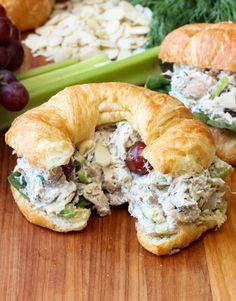 two croissants filled with chicken salad on top of a wooden cutting board