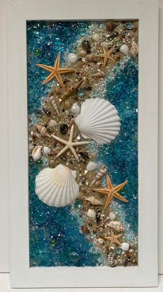 seashells and starfish on the beach framed in a white frame with blue water