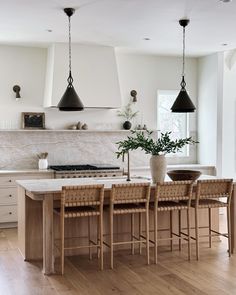 a kitchen with an island, stove and several stools in the middle of it