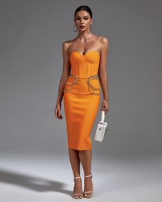 a woman in an orange dress holding a white purse