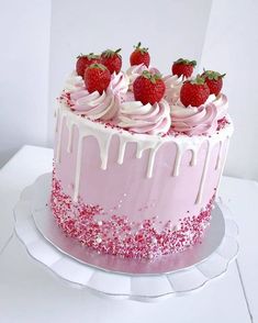 a pink cake with white icing and strawberries on top