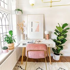 a white desk topped with a pink chair next to potted plants and a window