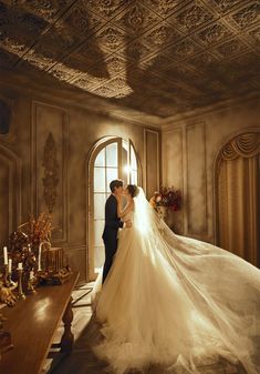 a bride and groom standing in front of a window