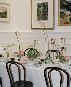 a dining table set with flowers and plates