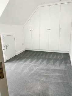 an empty room with white cupboards and carpeted flooring in the middle of it