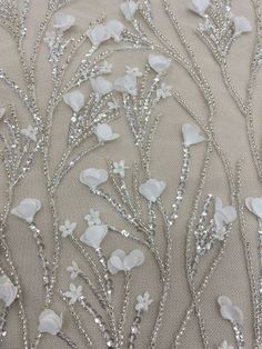 white flowers and leaves are on the side of a fabric with sequins in it