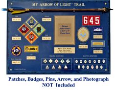 a blue sign with patches, pins, arrows and photos on it that says my arrow of light trail