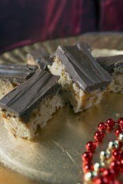 two pieces of chocolate bar on a plate with beaded necklace next to one piece