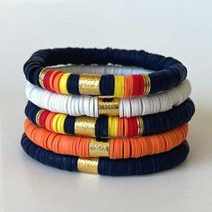 four different colored bracelets stacked on top of each other