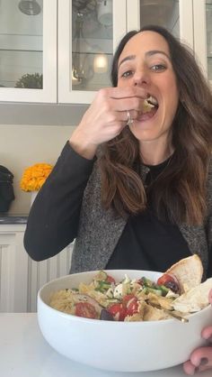 a woman eating food out of a white bowl