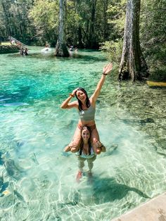 two women in the water with their arms up and one woman standing on her back