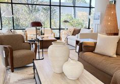 a living room with couches, chairs and lamps in front of large windows on the wall