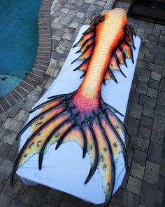 an artisticly painted bench on the side of a brick walkway next to a swimming pool