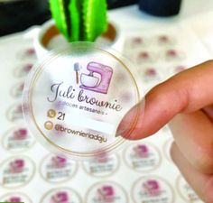 a person holding up a business card with a cactus in the background and stickers on it