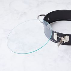 a pair of glasses sitting on top of a white table next to a black belt