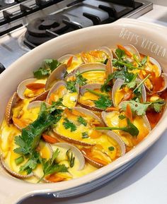 a white bowl filled with clams on top of a stove