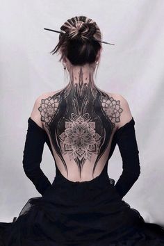 a woman with tattoos on her back sitting down