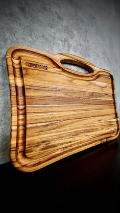 a wooden cutting board sitting on top of a black table next to a gray wall